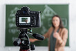© LIGHTFIELD STUDIOS - Blurred teacher standing near chalkboard and digital camera