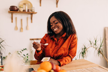 Wall Mural - Beautiful young woman eating yogurt in the kitchen in the morning. Healthy food. Portrait shot