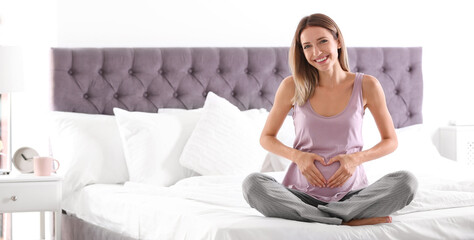 Wall Mural - Happy pregnant woman sitting in bed at home, space for text. Banner design