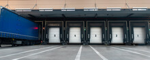 Innovative Modern Logistics Warehouse Center Complex Building Exterior Bay Gate Semi-trailer Unloading Goods Distribuition Warm Blue Sunset Sky Background. Cargo Storage Facility Industry Building