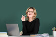 Pretty young high school or college teacher on the chalkboard. Young caucasian female teacher portrait with pointing finger on blackboard background.