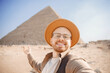 Happy tourist man in hat take selfie photo background pyramid of Egyptian , Cairo, Egypt. Concept travel life