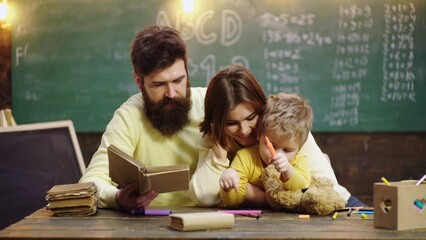 Fototapete - Cute clever boy study. Young mother father and little preschooler boy sit at table drawing together, playing, painting pictures in notebook, early development.