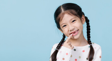 Wall Mural - 7 Years old child has loose tooth, Dentistry and Health care concept, Empty space isolated on blue background