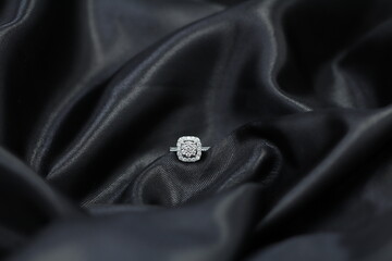 Fine jewelry as diamond ring with diamond with black satin fabric background. Jewelry shop concept