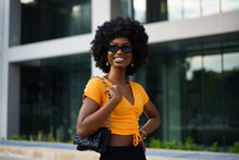 Photo Of A Stylish Young Black Woman With Curly Hair Wearing Orange Crop Top Walking In The Street