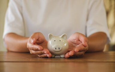 Wall Mural - Closeup image of a woman holding a piggy bank for saving money and financial concept