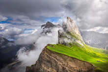 Seceda mountain near Ortisei in Dolomites. Beautiful italian landscape in Trentino. Clouds origins and born upon Seceda. Lord of the ring landscape with high slope with lot of green grass. Famous