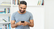 © Daniel Ernst - Laughing hispanic hipster man with beard sending message at mobile phone