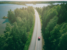 Aerial Top View Of Country Road Through Green Woods And Blue Lakes In Finland