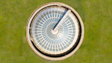 Perpendicular Aerial View On A Circular Glazing. Grass Grows Around It. From Above It Looks Like A Compass.