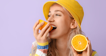 Sticker - Beautiful young blonde woman eating orange on lilac background