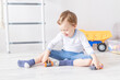© Any Grant - baby boy playing with wooden toys at home on the floor