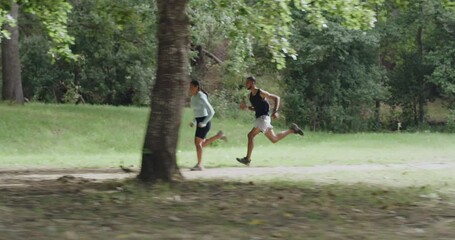 Sticker - Fit couple running a trail in a park or forest outdoors. Motivated and determined young athletes jogging with speed to increase endurance and stamina during a cardio training workout in nature