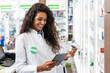 Female pharmacist working in pharmacy using digital tablet during inventory.
