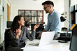 © JustLife - Colleagues in office. Businesswoman and businessman discussing work in office