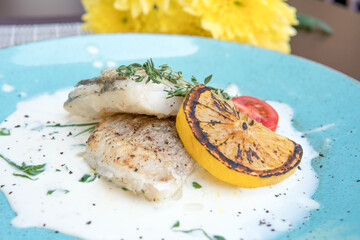 Fried walleye fillet, in creamy sauce with microgreens and lemon