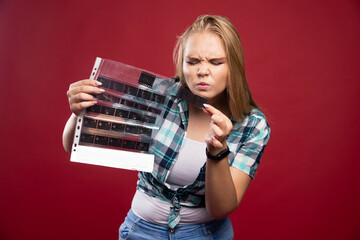 Wall Mural - Young blonde model checks the polaroid film scenes and looks dissatisfied and terrified