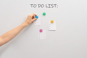 Image of white board and hand attaching pieces of paper to the magnetic board.