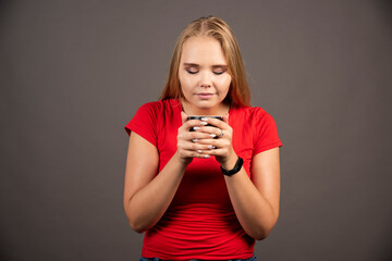 Happy woman looking at cup of tea on dark background