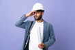 © luismolinero - Young architect Moroccan man with helmet and holding blueprints over isolated background doing surprise gesture while looking to the side