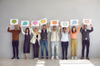 © Studio Romantic - Full body length group happy diverse multiracial multiethnic people showing various paper sheets, cards and banners with pictures of different speech clouds and message bubbles. Communication concept