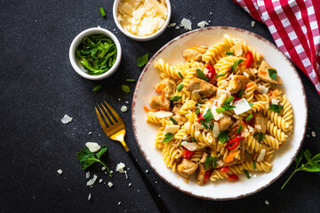 Pasta with turkey meat, vegetables and parmesan on dark stone table. Top view with space for recipe.