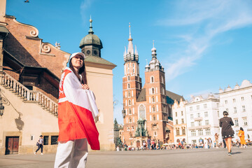 Sticker - woman traveler covered with poland flag at the center of Krakow town