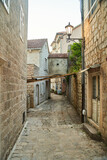 Fototapeta Uliczki - Empty narrow street with ancient stone buildings in old town Herceg Novi, Montenegro. High quality photo