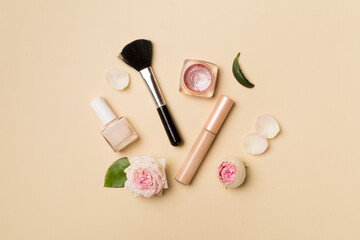 Makeup products with flowers on color background, top view