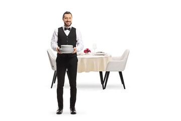 Poster - Full length portrait of a server holding a pile of plates and standing in front of a table