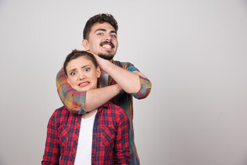 Young man holding woman's head on a gray wall