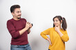 © rastockinc - Cute couple taking pictures with camera and posing over a white wall