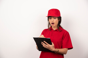 Wall Mural - Young worker with red uniform and clipboard on white background