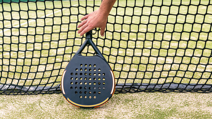 Wall Mural - Professional monitor of padel holding black racket behind the net. Game concept