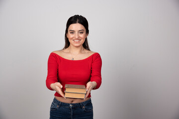 Portrait of a smiling woman giving two books