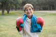 © Vane Nunes - Senior woman smiling on camera after boxing training routine outside at city park - Focus on gloves
