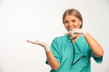 Blonde female doctor in blue uniform with stethoscope in the neck pointing something