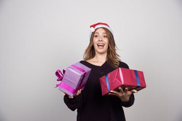 Young woman with Santa hat holding gift boxes presents