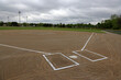 A wide angle shot of an unoccupied baseball field on a cloudy day.