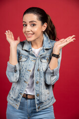 Wall Mural - Beautiful woman in denim outfit posing on red background