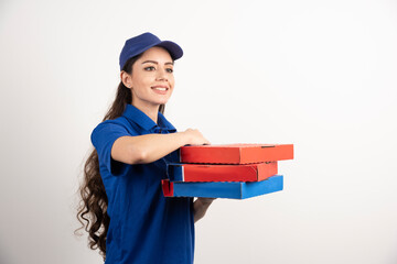 Wall Mural - Happy smiling delivery girl in blue uniform with takeaway pizza boxes over white background