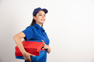 Wall Mural - Happy smiling delivery girl in blue uniform with takeaway pizza boxes over white background