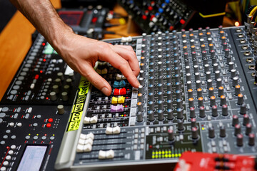 Wall Mural - Hand of a sound engineer on sound console mixer. Equalizer control