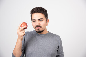 Young man holding red apple angrily