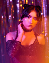 Portrait Of A Young Woman At A Neon Party,  Orange Lens Flare,  Blurred Background With Colored Sparkles