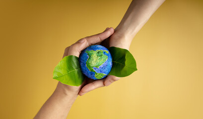 World Earth Day Concept. Green Energy, ESG, Renewable and Sustainable Resources. Environmental and Ecology Care. Hands of People  Embracing Green Leaf and Handmade Globe