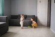 Children siblings with mop clean in real bright living room