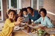 © Drazen - Happy black multi-generation family taking selfie during lunch at dining table.