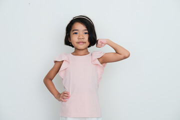 Wall Mural - Asian little girl showing her bicep muscle with confident expression